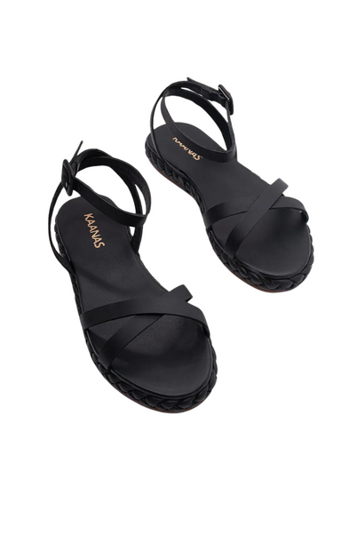 The Iyari Crisscross Sandal by Kaanas features braided leather straps that wrap the midsole and a slim ankle strap with buckle closure. Black sandal.