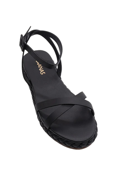 The Iyari Crisscross Sandal by Kaanas features braided leather straps that wrap the midsole and a slim ankle strap with buckle closure. Black sandal.